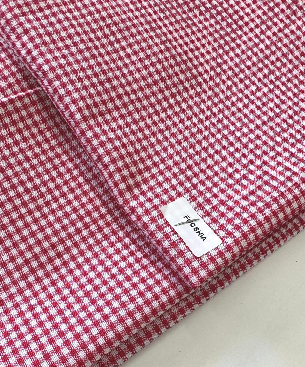 Close-up of folded fuchsia and white 1/8-inch gingham check fabric, showing a crisp, small-scale checkered pattern with a textured weave. Gingham Checked Fabric by Yard 1/8” inch Poly Cotton Checkered Fabric for Tablecloth Dress Curtains, Multiple Colors Available