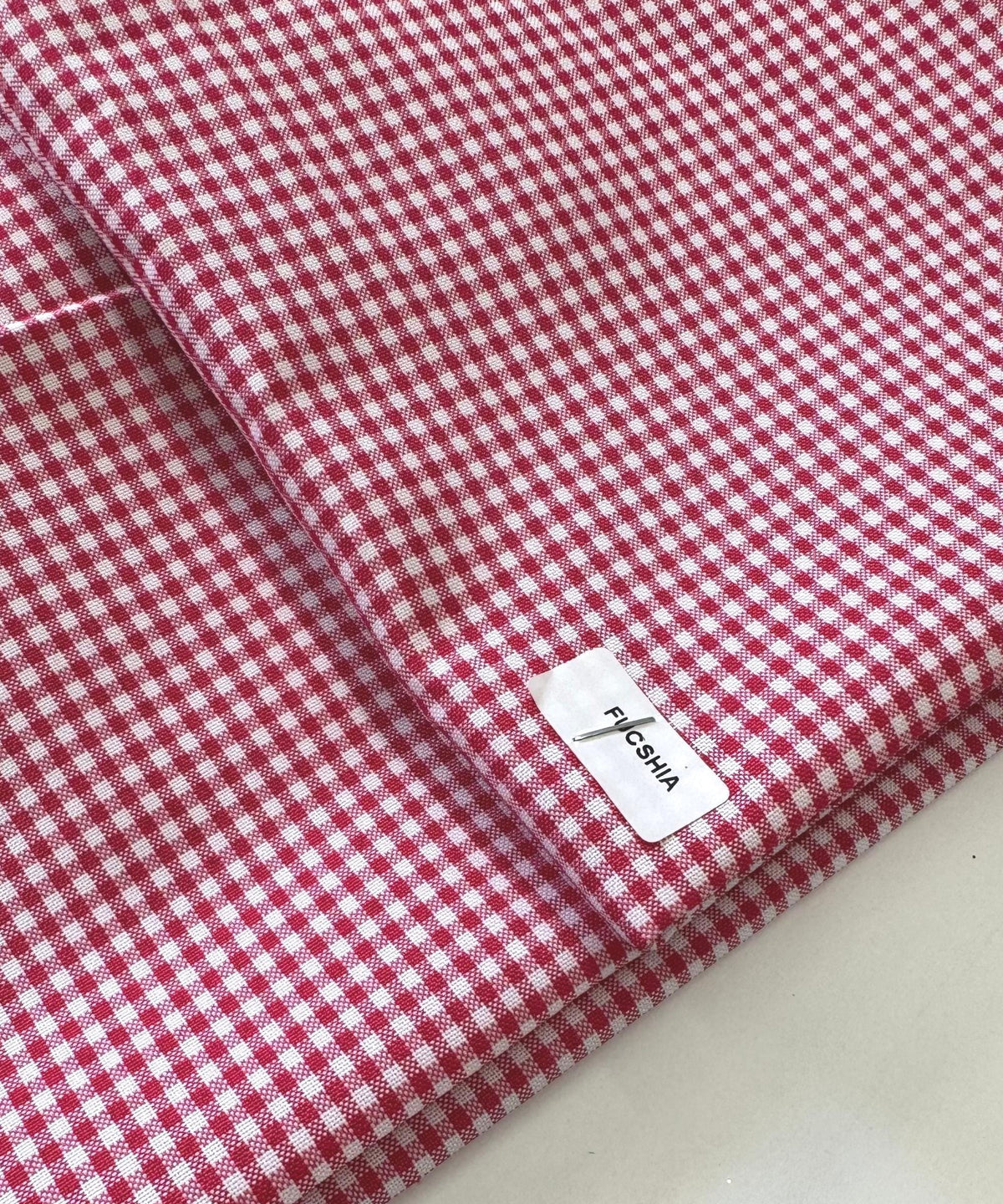 Close-up of folded fuchsia and white 1/8-inch gingham check fabric, showing a crisp, small-scale checkered pattern with a textured weave. Gingham Checked Fabric by Yard 1/8” inch Poly Cotton Checkered Fabric for Tablecloth Dress Curtains, Multiple Colors Available